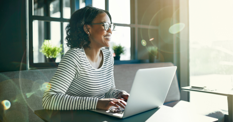 Woman smiling while planning a Giving Tuesday campaign at her computer.