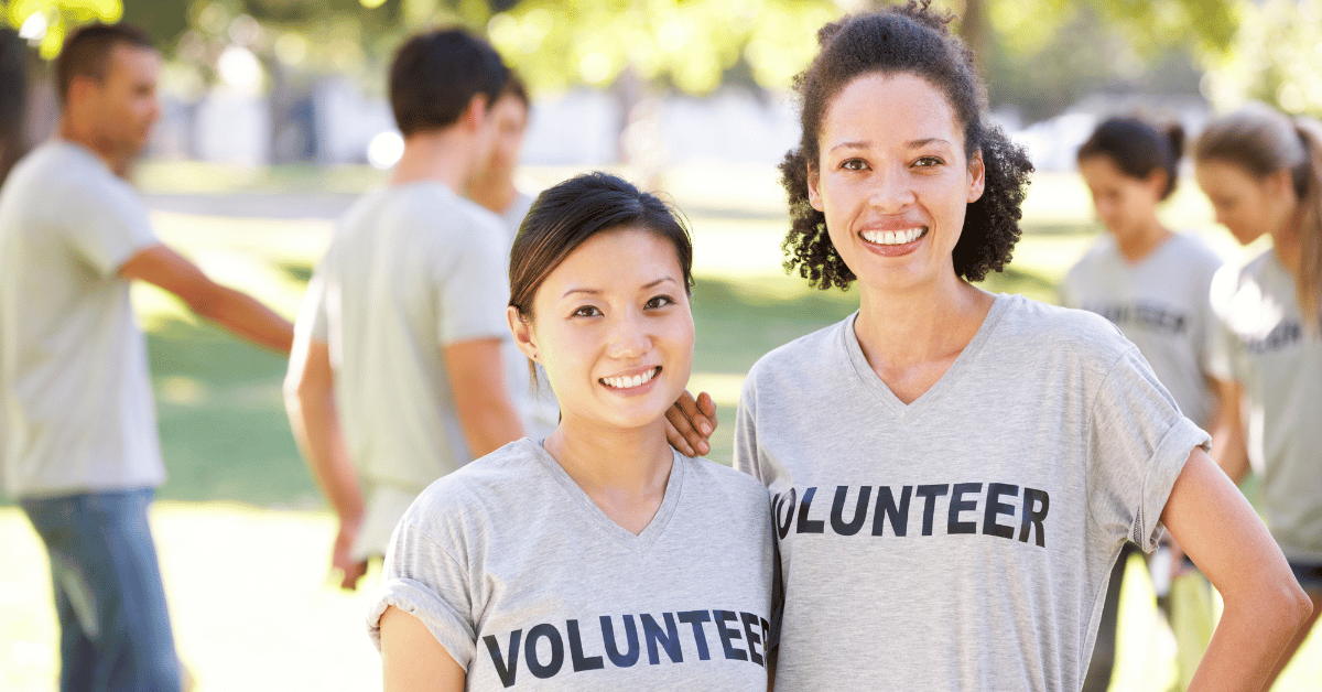 Two nonprofit volunteers pose for a picture with big smiles on their faces.