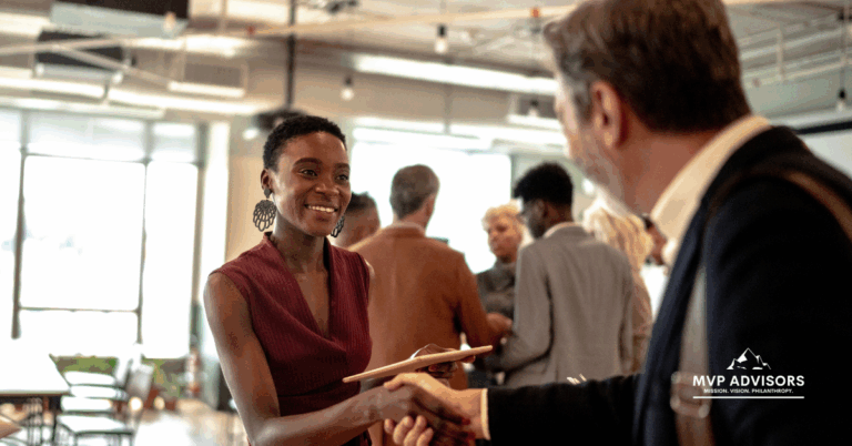 Blog header image for How to Say Thank You to Donors showing a young business woman shaking the hand of a business man at an event